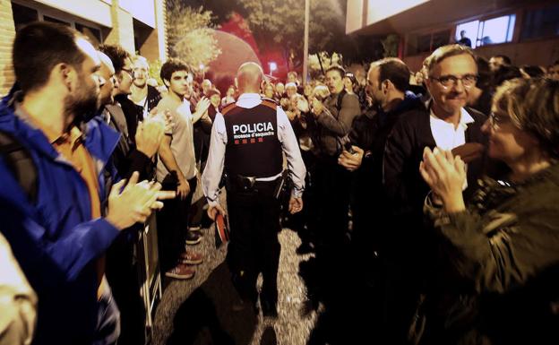 Una pareja de Mossos d'Esquadra salen entre aplausos de una escuela del barrio de Sarriá de Barcelona./EFE