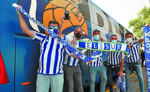 Un grupo de cinco aficionados junto al autobús de la Real en Sevilla. /MORQUECHO