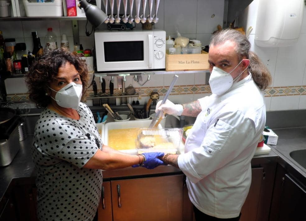 Félix Manso y Sonia García rellenando tuppers en la cocina. / F. DE LA HERA
