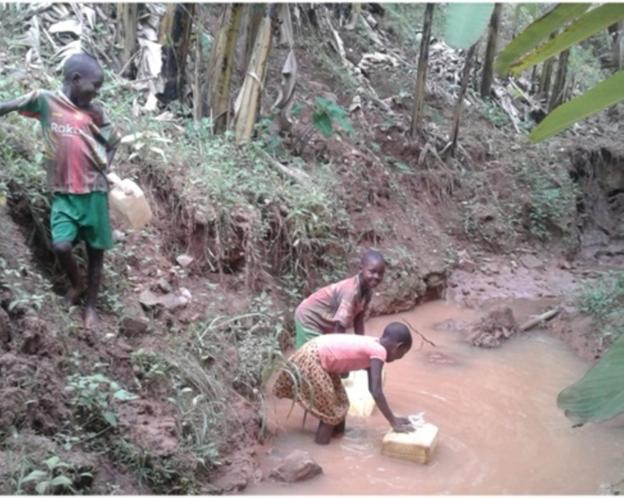 Dos niñas llenan sus bidones de agua en una poza en Kabuga. / BEHAR BIDASOA