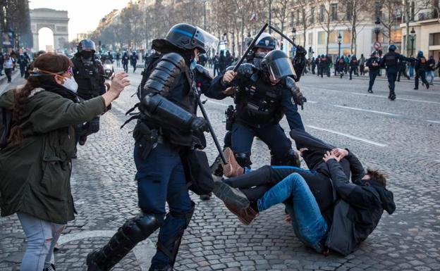 French agents charge against young protesters on the Champs Elysées.
