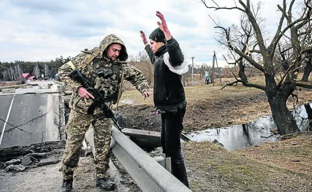 A Ukrainian soldier searches a citizen to check what he is wearing under his jacket, suspecting that he is an infiltrator. 