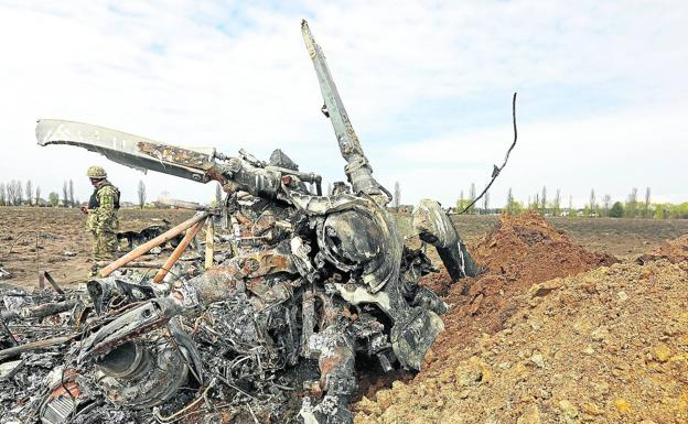 A Ukrainian military man walks past the wreckage of a Russian helicopter in the kyiv region.