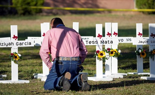 Duel.  Pastor Daniel Myers prays in front of the funeral crosses of the victims of the massacre at Robb Elementary School.