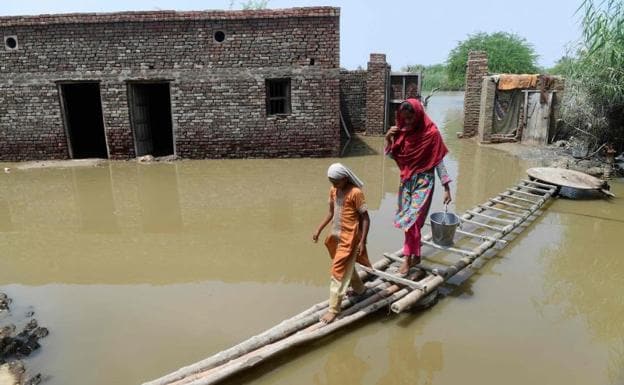 A woman and a girl try to cross the flooded streets of Shikarpur town. 