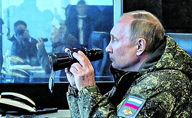 Vladimir Putin, in camouflage clothing, watches the Vostok-2022 military rehearsals.