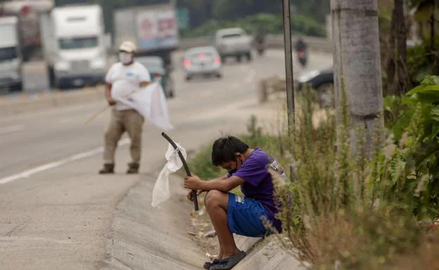 A child waves a white flag on the road asking for help for hunger due to the economic crisis in El Tejar (Guatemala).  Guatemala. 