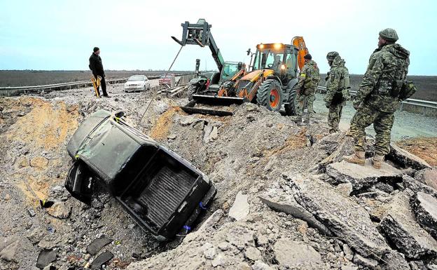 Ukrainian soldiers remove a car from a crater on the road leading to the recently liberated Kherson region.