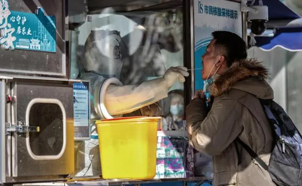 A toilet performs a PCR test on a citizen in Shanghai through a protective screen. 