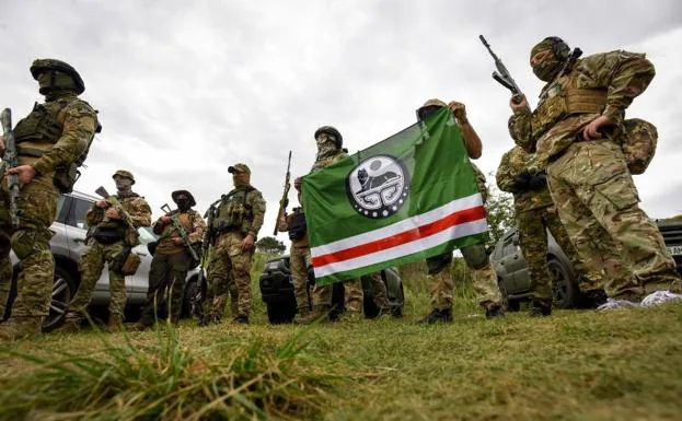 Volunteers from the Dzhokhar Dudayev Battalion pose with a flag of the so-called Chechen Republic of Ichkeria, during a military exercise near kyiv on August 28, 2022.