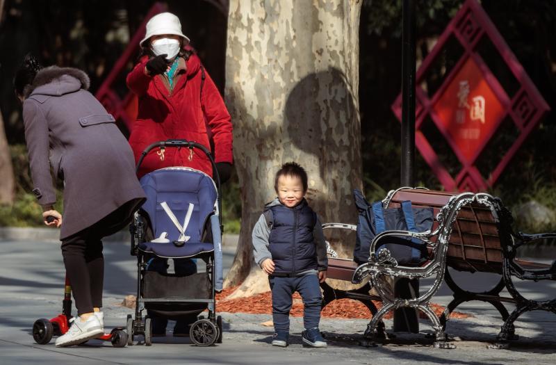 A woman walks with her two children in a park in Shanghai after the lifting of health restrictions this month